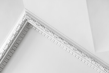Elegant white interior details, decorative plaster ceiling corner with ornate molding and classic cornice corner. Minimal composition emphasizes texture, symmetry and historic architectural charm © evannovostro