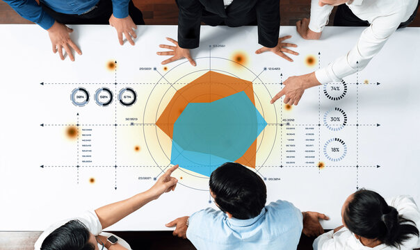 A diverse group of business professionals gather around a large table, engaged in collaborative analysis of data visualizations and statistics to drive strategic decisions. Trope