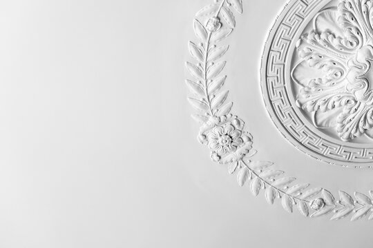 Ornate white plaster ceiling medallion with decorative floral molding, showcasing classical relief detail and elegant texture ideal for architecture, interior design, restoration and luxury decor