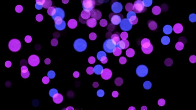 Purple and blue bokeh lights floating on empty black background. An abstract, blurred image features bokeh lights in shades of blue and purple against a dark background.