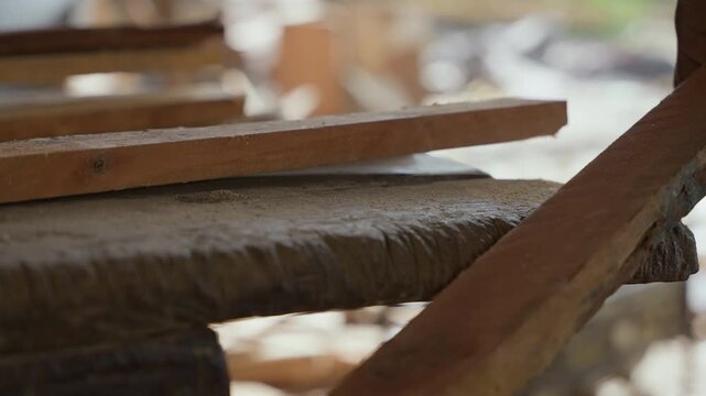 Handsaw resting on wooden bench plank ready for cut, blade edge catching soft sunlight, textured grain and fine shavings on rough work surface, worn handle and metal teeth in sharp focus, quiet