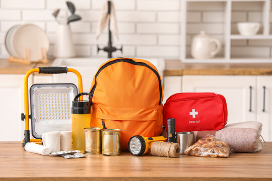 Orange emergency backpack with necessities on table in kitchen