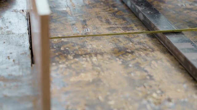 Empty workbench with stretched guide string across surface, precise layout for carpentry project with straightedge and tape aligned for cabinet panel setup, worn tabletop showing grain and scuff