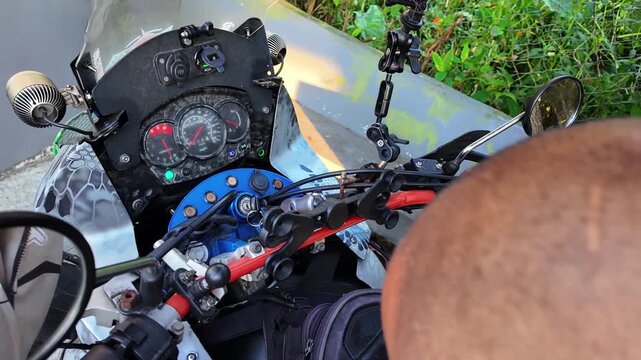 detailed point-of-view shot of rider engaging the ignition switch and gripping the handlebars of adventure motorcycle, preparing for a journey through the mountain roads