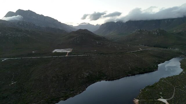 Aerial Reflective Lake Framed By Mountains With Calm Mirror Surface And Pastel Sky, Soft Dawn Light