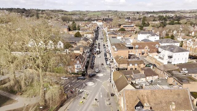 Aerial drone footage flying over Marlow High Street in Buckinghamshire, England, following the road in a northerly direction. Scenic view of a traditional British town with shops & buildings.