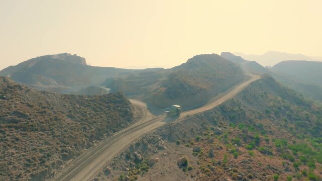 Aerial shot of EV mining dump truck driving on a mountain road in Pakistan.