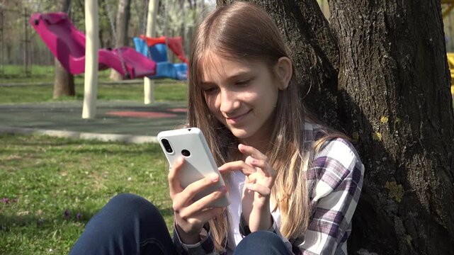 Girl Playing Smartphone by Tree, Teenager Kid Browsing Internet on Smart Phone in Park, Adolescent Child Outdoor at Playground
