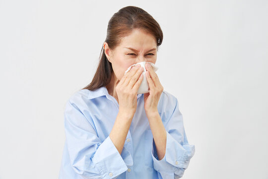 白背景で鼻をかむ女性