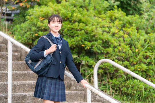 Middle school, high school, and elementary school students in their uniforms descending the stairs of the school building.
