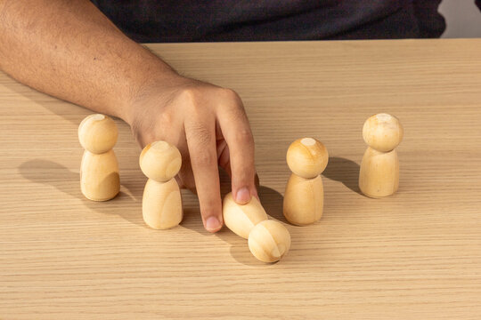 Hand Overturning Wooden Peg Doll for Leadership Downfall and Crisis Concept
