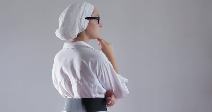 Business goal-oriented young woman in glasses and turban thought. View from the back.