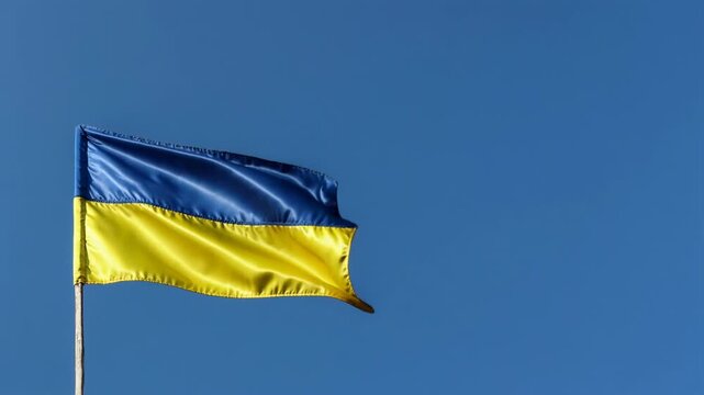 National flag of ukraine waving on a flagpole against a clear blue sky on a sunny day