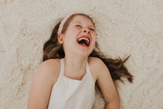 Young girl with blue eyes lays on blanket while looking at camera