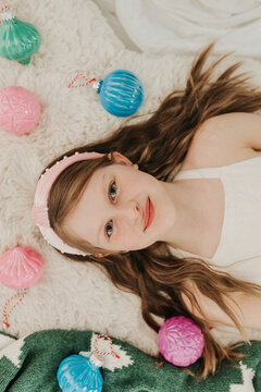 Girl looks up at camera while surrounded by colorful ornaments