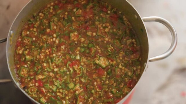 Overhead pot of chunky okra stew on stovetop, fiveframe sequence highlights vibrant red and green vegetables, glossy broth, marketfresh feel, serving and plating ideas for cozy meal
