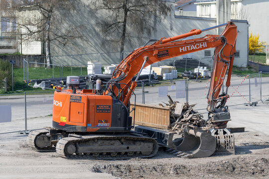 Mirecourt, France - March 21st 2026 : View on an orange crawler excavator Hitachi ZX225USLC-6 for the demolition of a building on a construction site.