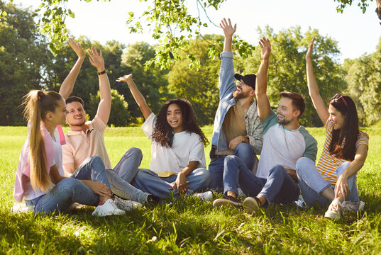 Diverse group of friends, people sitting together in circle, green sunny outdoor park, interacting, relaxed sociable team, enjoying happy time outdoors in green grassy park, engaged in conversation 