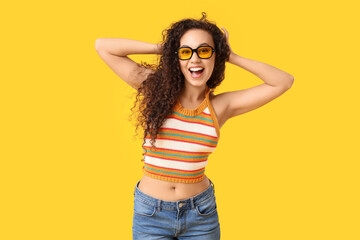 Naklejka na ściany i meble Beautiful African-American woman with sunglasses on yellow background