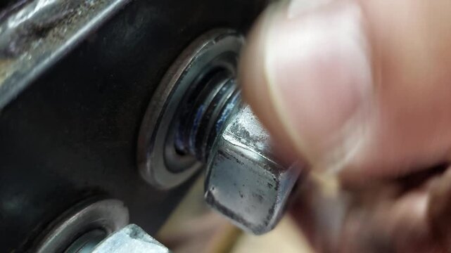 Detailed View of a Hand Screwing a Large Hex Nut onto a Threaded Bolt