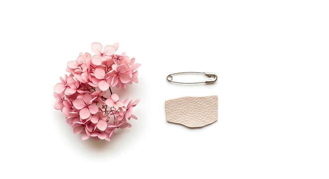 Pink hydrangea flower, safety pin, and a piece of textured leather isolated on white background
