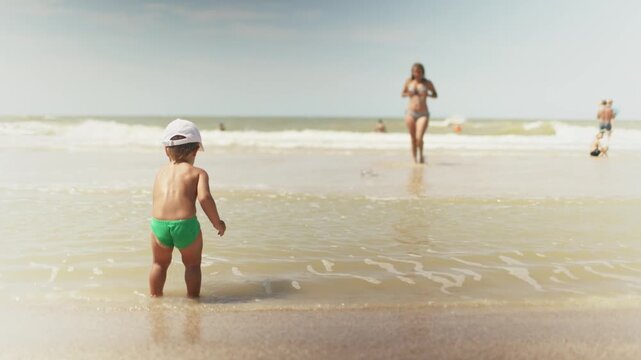 Kid collects shells and pebbles in the sea on a sandy bottom under the summer sun on a vacation