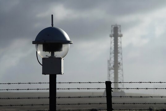 A prison watchtower and barbed wire fence suggest confinement and surveillance.