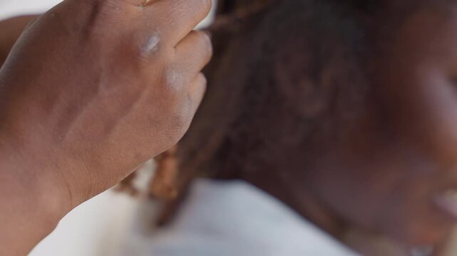 Closeup hands dusted with styling powder and finishing touch on braid, senior stylist tapping and pressing to set matte texture, intimate salon angle with concentrated handwork and calm focused energy