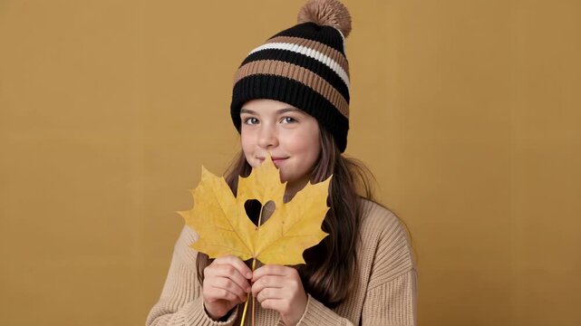 Young Girl Holding Autumn Maple Leaf with Heart Shape Smiling at Camera in Studio for Seasonal Lifestyle and Holiday Content