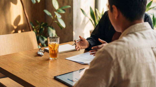 Professional photograph of two colleagues discussing business documents and a tablet during a collaborative meeting.