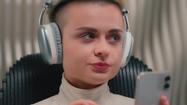 Close up woman Caucasian girl wearing wireless headphones typing phone choosing song sound effects music editing video online listen audio thinking hesitate female in futuristic space futurism room