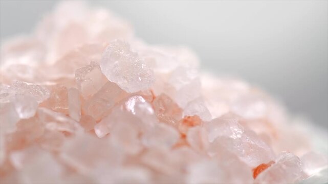Pink Himalayan salt, Himalayan salt crystals close up. Pink coarse salt crystals macro shot, rotating over gray background, slow motion video. 