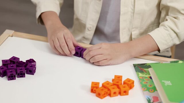 Child Sorting and Connecting Colorful Math Manipulative Blocks in Classroom