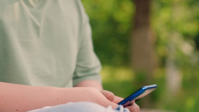 boy enjoys mobile internet game, boy with smartphone playing mobile game online in green park., smiling boy plays smartphone game online while relaxing in nature., child gamer holding smartphone