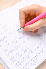Obraz premium Woman writing maths formulas in copybook with pen, closeup
