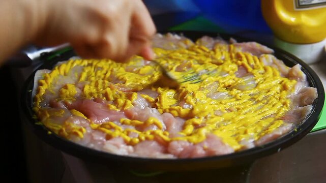 Raw chicken breast being seasoned and prepared for cooking.