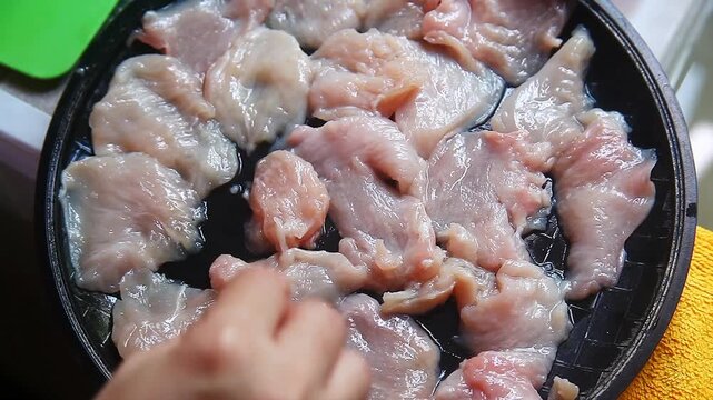 Fresh raw chicken breast fillet being cut with a knife