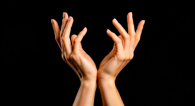 Two elegant female hands with natural manicure reaching up and cupping together isolated on black background for beauty and care concept