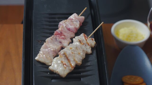 ろばた焼きグリルでこんがりと焼ける豚串（やきとん）のクローズアップ
