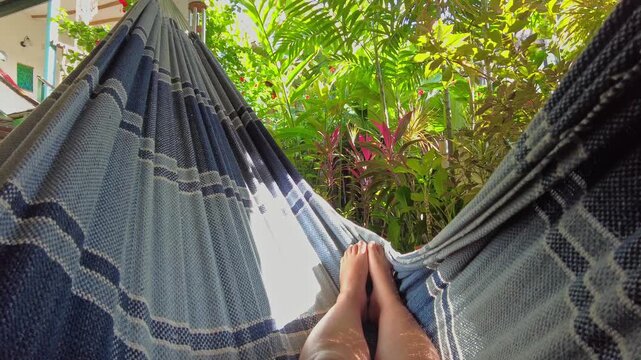 POV shot showing them swaying in a hammock overlooking a lush green garden at a rental property in the beach town of Choroni, Aragua, Venezuela