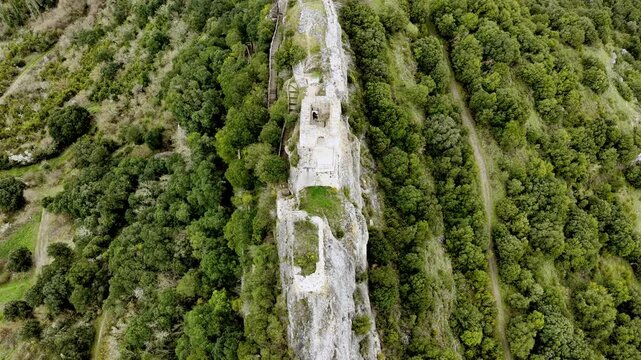 Vista a&eacute;rea cinematogr&aacute;fica de una fortaleza medieval en ruinas sobre un escarpado risco, con muros de piedra dominando el paisaje y evocando historia y car&aacute;cter.