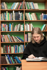 Young man reading book in public library