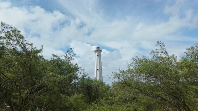 Aerial view of the striking Mercusuar Samas Lighthouse surrounded by lush green trees, contrasting with the clear sky, Bantul Regency, Indonesia.