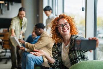 Obraz premium Young woman taking selfie with smart phone in office