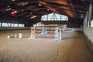 Fotobehang Paardrijden Indoor equestrian arena ready for show jumping with various colorful hurdles  © Juanmarcos