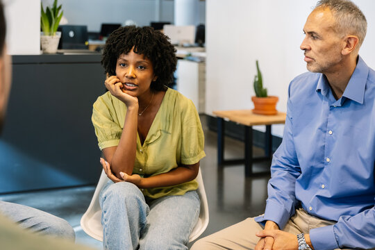 Diverse business professionals actively participating in a corporate meeting, collaborating on ideas and sharing insights while sitting together in a modern office environment