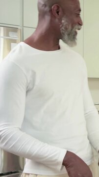 Vertical video: Preparing fruit in kitchen, man in shirt hugging her on arrival, resuming at board