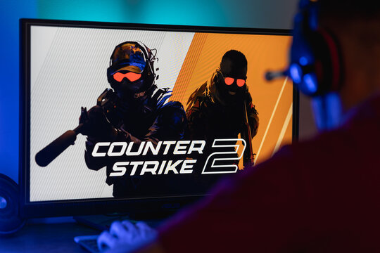 Gamer sitting in front of a computer monitor with Counter-Strike 2 logo on screen, esports fan ready to play tactical first-person shooter video game.