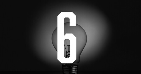 Featuring clear incandescent bulb on flat dark surface showing filament, metal base and numeral 6 © vectorfusionart