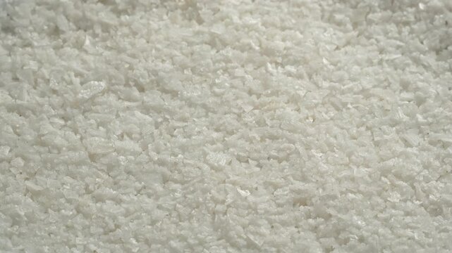 Macro rotating background of coarse white sea salt crystals. Pure raw mineral texture for premium culinary, health, and spa wellness projects.